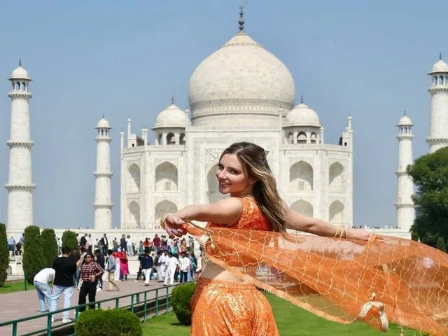 Femme en robe orange posant devant le Taj Mahal