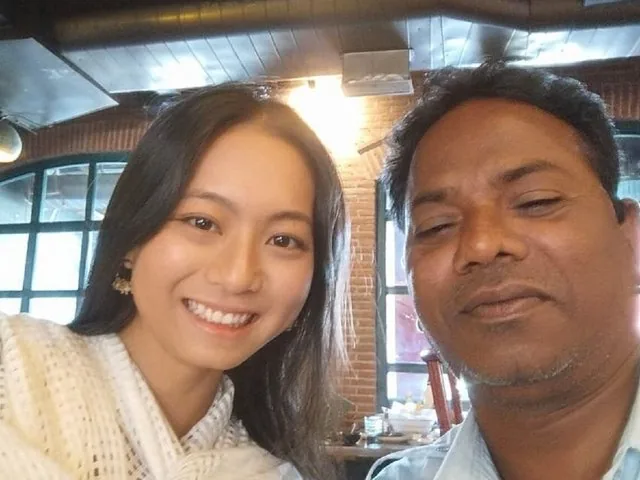 A close-up selfie of two people smiling indoors at a restaurant