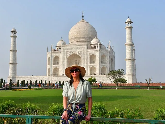 Woman in straw hat posing in front of the Taj Mahal.