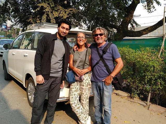 Guide touristique posant avec un couple à côté d'un SUV blanc dans la rue