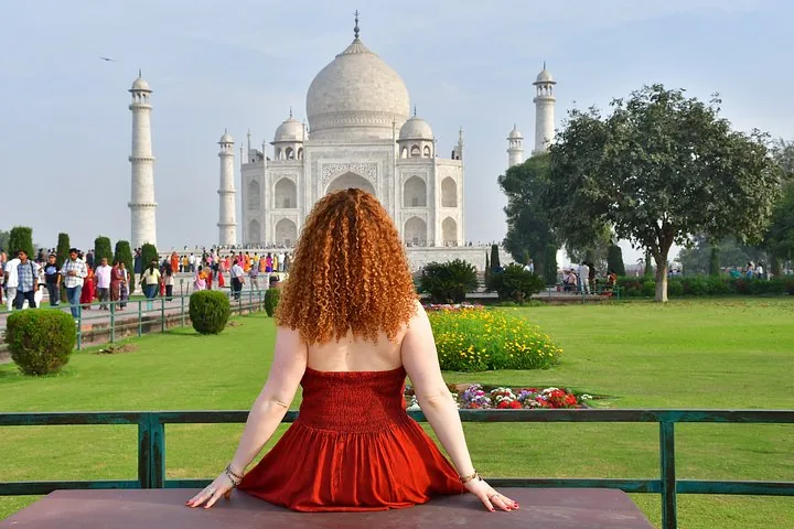 Femme aux cheveux roux bouclés face au Taj Mahal, de dos.